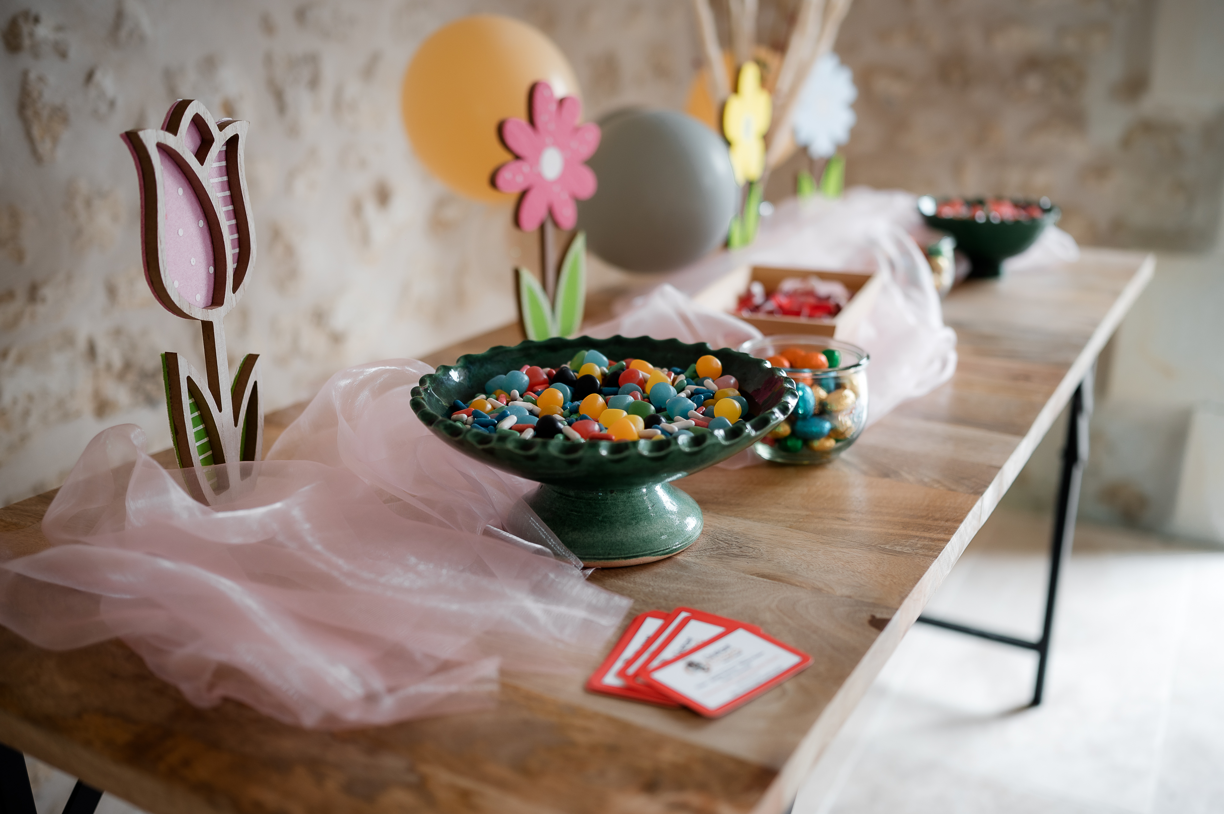 Décoration table fête avec bonbons et fleurs colorées.