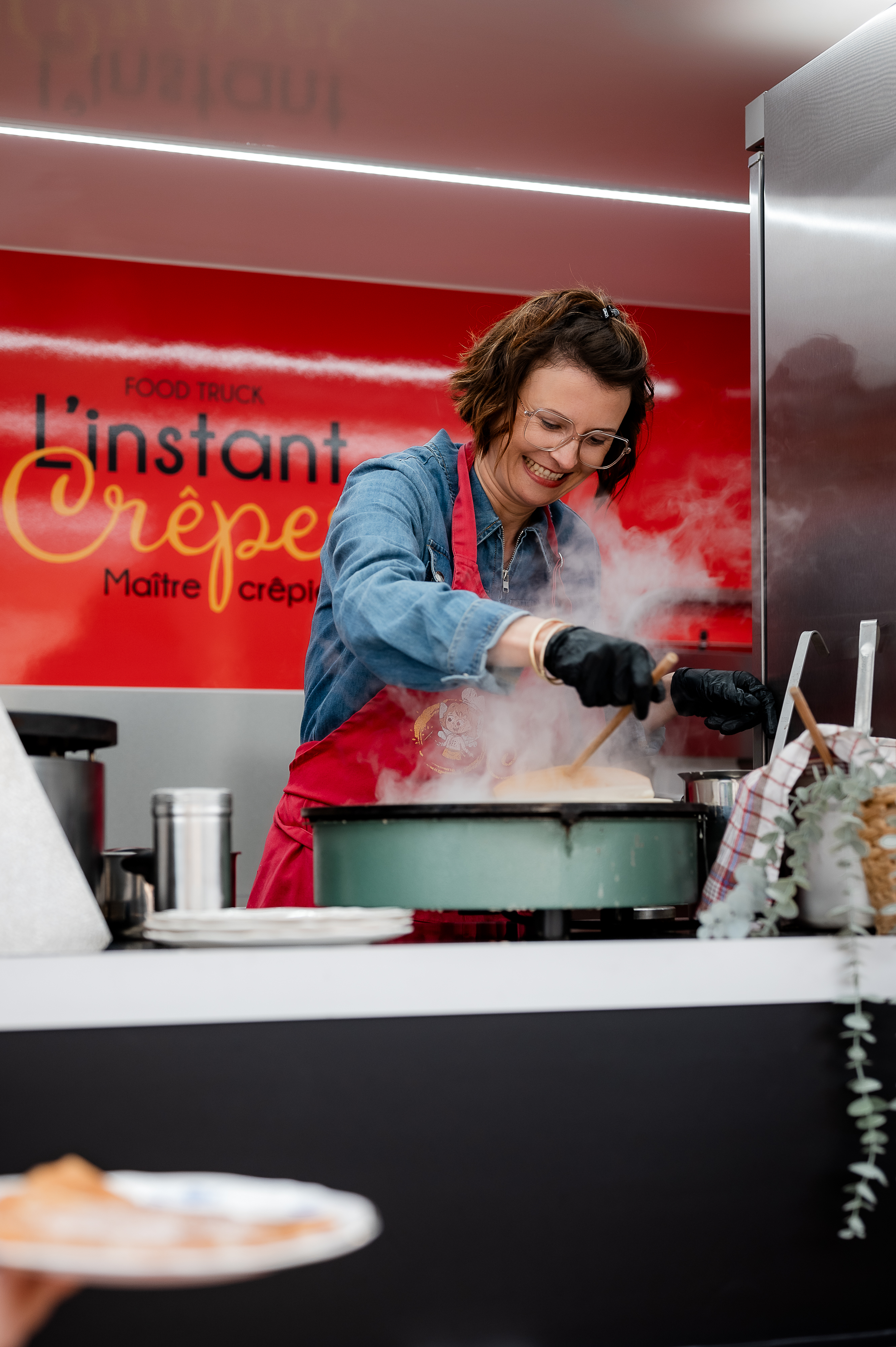 Crêpière souriante travaillant dans un food truck.